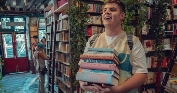 Isaac dans une librairie, une pile de livre dans les mains